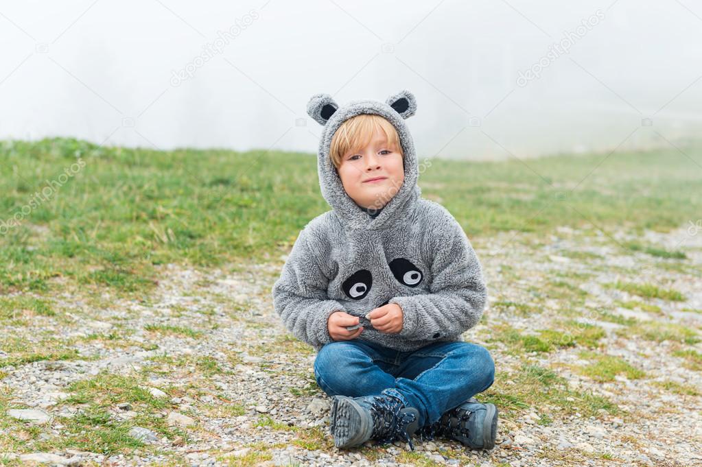 Cute little boy playing outdoors on a very foggy day, wearing funny grey sweatshirt