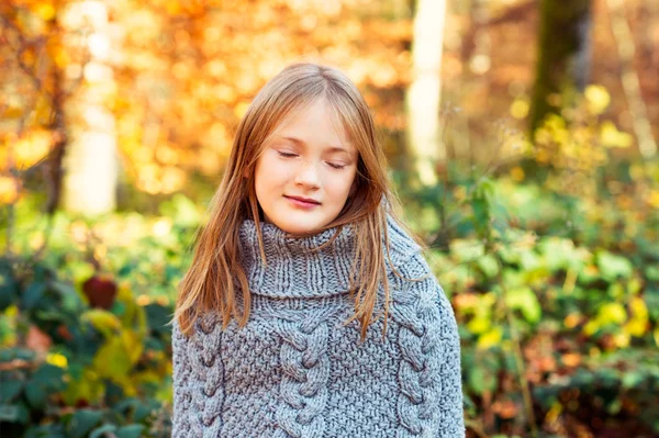 Ritratto all'aperto di una graziosa bambina nella foresta autunnale, con poncho grigio a maglia, occhi chiusi — Foto Stock