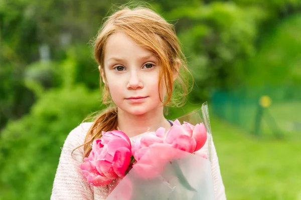 Utomhus porträtt av en söt liten rödhårig flicka, hålla bukett rosa pioner — Stockfoto