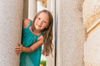 Açık havada bir şehirde dolaşan yeşil top, giyen sevimli küçük bir kız portresi yaz