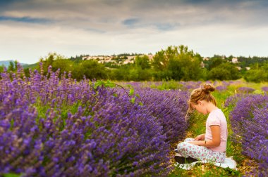 Sevimli küçük kız güzel bir güneşli akşam lavanta alan bir kitap okuma