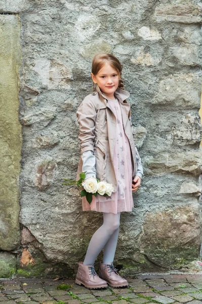Retrato ao ar livre de uma menina bonito com rosas brancas, vestindo casaco bege e vestido rosa — Fotografia de Stock
