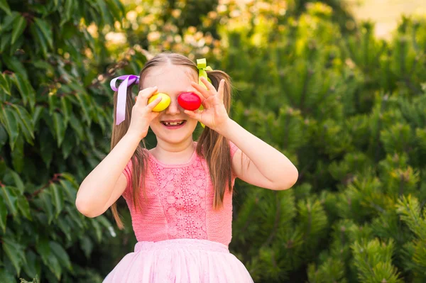 Niedliches kleines Mädchen mit 2 Zöpfen spielt im Park, Eiersuche — Stockfoto