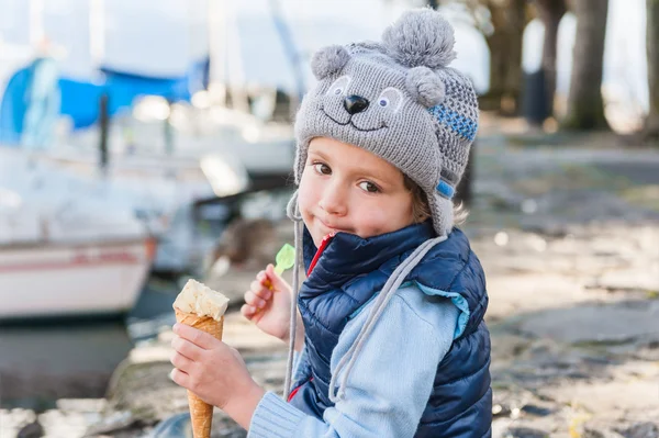 Внешний портрет забавного мальчика, поедающего мороженое, в зимней шляпе — стоковое фото