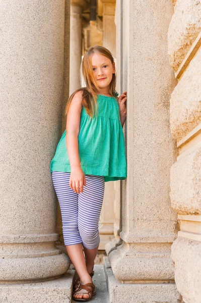 Summer portrait of a cute little girl wearing green top, plying outdoors in a city — Stock Photo, Image