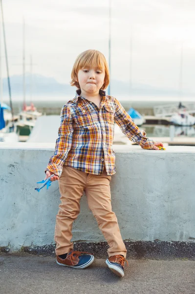 Retrato al aire libre de un lindo niño de moda de 4 años, con camisa a cuadros amarilla, pantalones beige y zapatillas de deporte. — Foto de Stock