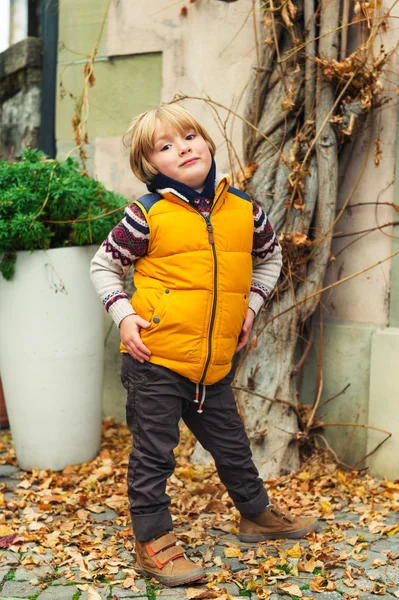 Retrato ao ar livre de um menino bonito de 4-5 anos, vestindo colete amarelo quente — Fotografia de Stock