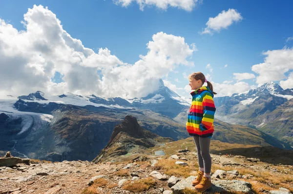 Söt liten flicka klädd i ljusa rainbow färgad päls och beige stövlar, vilar i bergen, Schweiz — Stockfoto