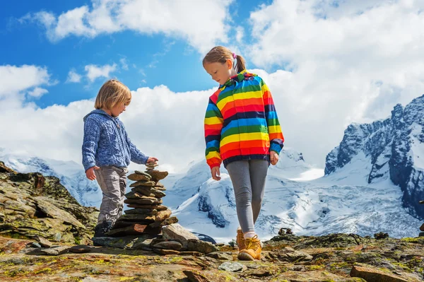 Crianças bonitinhas descansando no glaciar Gornergrat, Suíça, duas crianças brincando juntas nas montanhas, menino pequeno e sua irmã mais velha caminhando nos Alpes Suíços, vestindo roupas coloridas — Fotografia de Stock