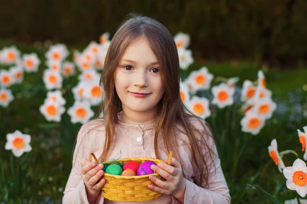 カラフルなイースターエッグと小さなバスケットを持って春の庭にかわいい小さな女の子の屋外のポートレート — ストック写真