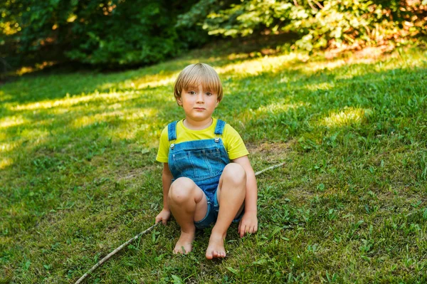 Kleine jongen buiten spelen op een mooie zonnige zomerdag dragen denim overall — Stockfoto