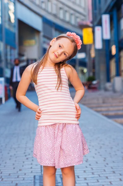 Outdoor fashion portrait of a cute little girl of 7-8 years old, wearing pink top, skirt and headband — 스톡 사진