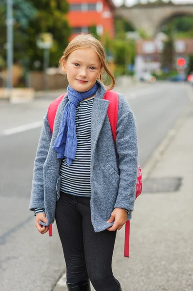 Außenporträt eines niedlichen kleinen Mädchens mit grauem Mantel und rotem Rucksack — Stockfoto