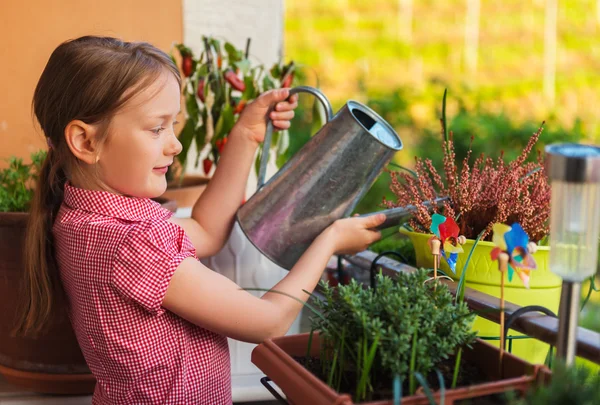 Aranyos kislány, öntözés növények, az erkélyen, egy szép napsütéses napon — Stock Fotó