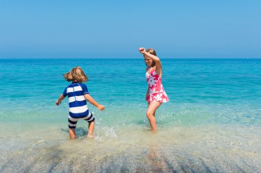 Two kids having fun on summer vacation, playing in the sea, image taken in Tropea, Calabria, Italy
