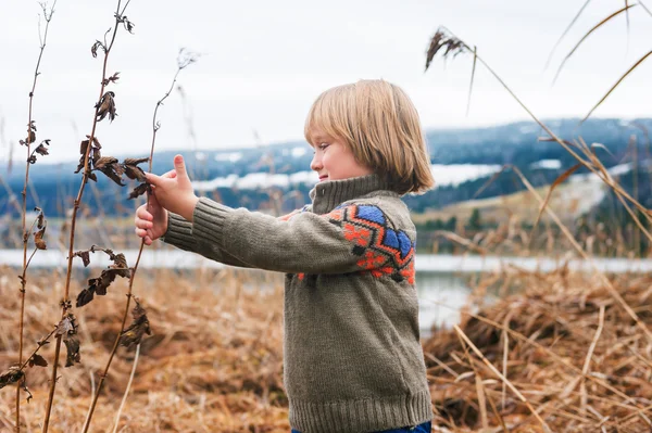 Открытый портрет милого мальчика 4-5 лет, играющего у озера в холодный день — стоковое фото
