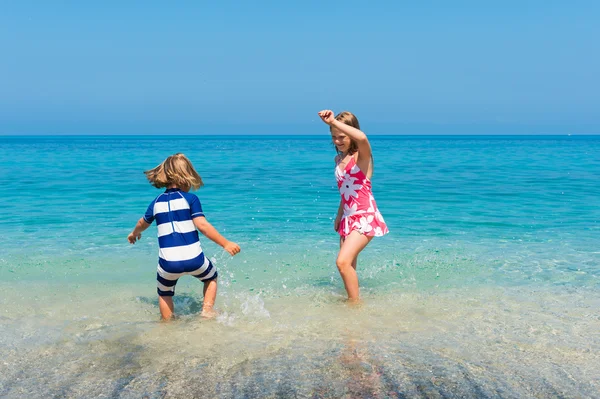 Two kids having fun on summer vacation, playing in the sea, image taken in Tropea, Calabria, Italy — Stock Photo, Image