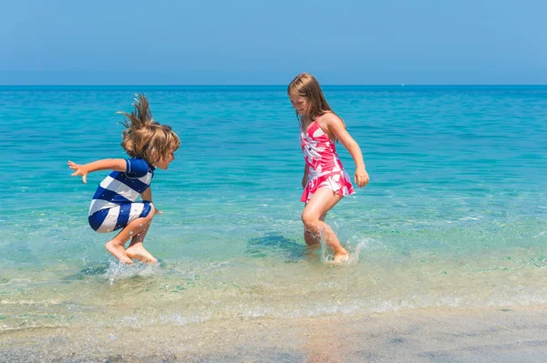 Two kids having fun on summer vacation, playing in the sea, image taken in Tropea, Calabria, Italy — Stock Photo, Image