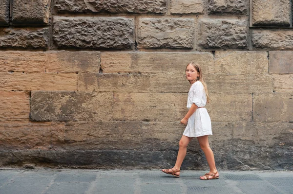 Kültéri divat-portré egy szép kislány, rajta a fehér ruha és a nyári szandál — Stock Fotó
