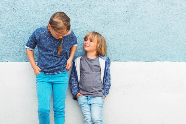 Twee kinderen, meisje en kleine jongen, die zich voordeed buiten, permanent tegen blauwe muur — Stockfoto