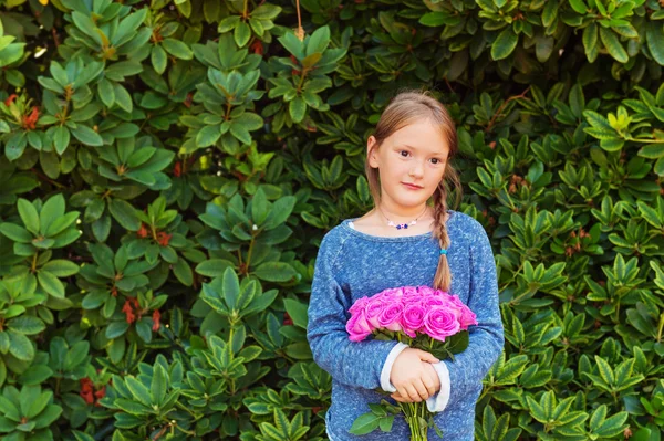 Utomhus porträtt av bedårande liten flicka på 7-8 år gammal, håller vacker bukett av ljusa rosa rosor — Stockfoto