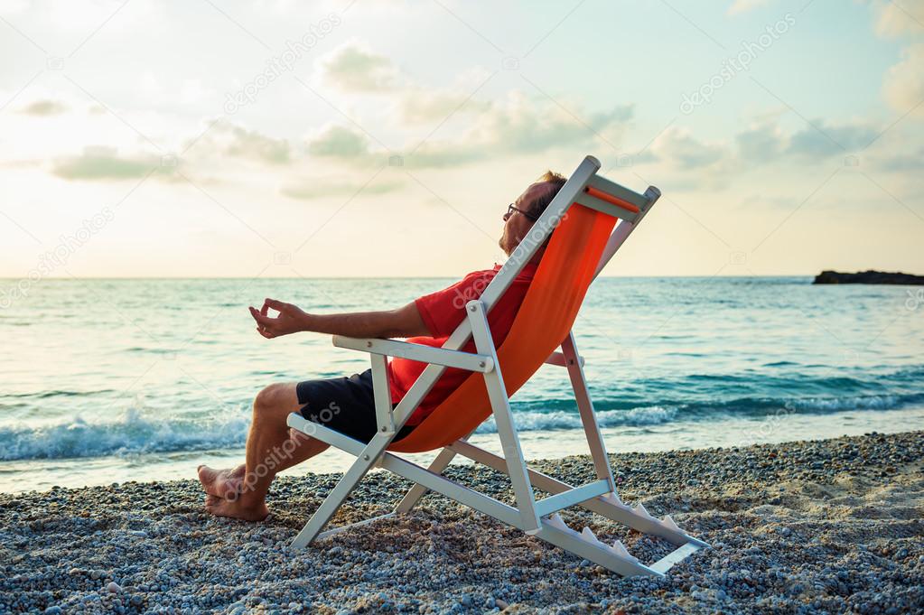 Man relaxing on beach at sunset