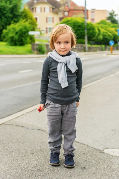 Outdoor Portret van een leuke mode jongen in de straat, dragen, grijze kleding en donker blauwe schoenen — Stockfoto