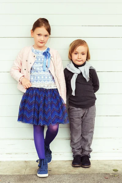 Twee mode kinderen tegen witte houten muur — Stockfoto