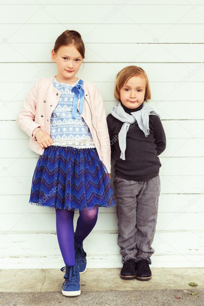 Two fashion kids against white wooden wall