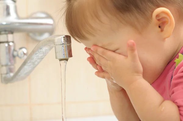 Kleine baby wassen van haar gezicht — Stockfoto