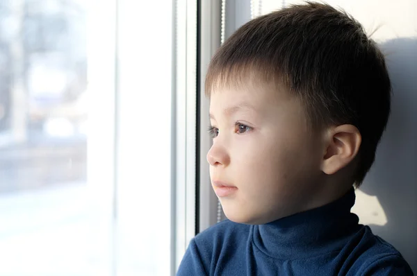 Pojke tittar ut genom fönstret och tänker filosofiska — Stockfoto