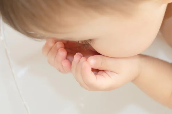 Bebê sedento bebendo das palmas das mãos — Fotografia de Stock