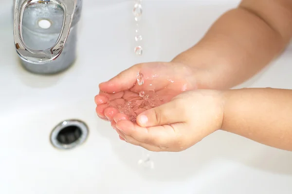 Καθαρό νερό από τη βαλβίδα του νερού σε μωρό παιδί παλάμες — Φωτογραφία Αρχείου