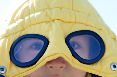 Portre dışarıda gözlüklü sarı montlu çocuk