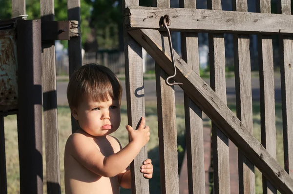Baby girl near fence outdoor at summer with bronze tan — Stock Photo, Image
