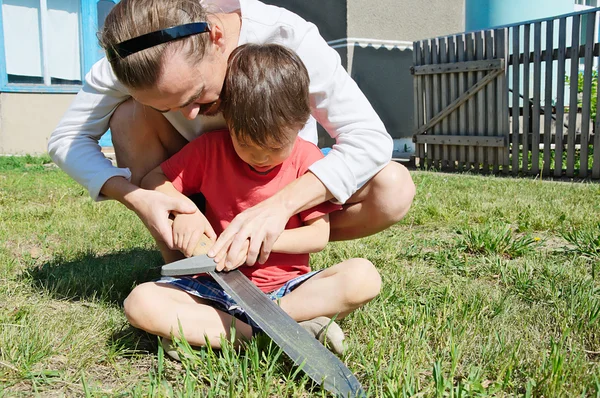 Papa lehrt Jungen beim Machetenschleifen — Stockfoto