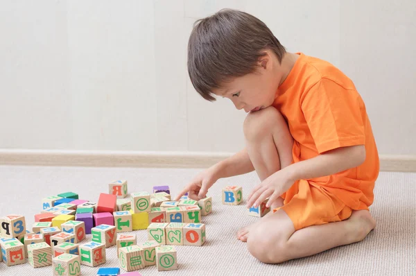 Niño jugando con cubos de juguete en la habitación — Foto de Stock