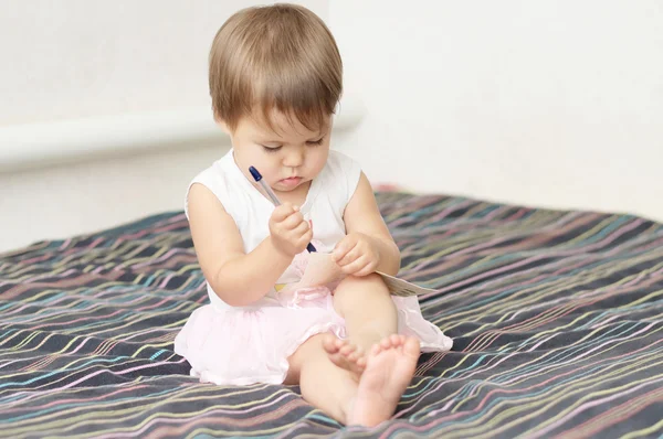 Adorable niña haciendo su primer golpe de pluma — Foto de Stock