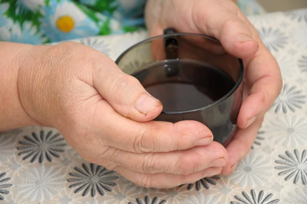 Old Hands warming with cap of tea — Stock Photo, Image