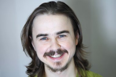 Sakallı adam gülümsüyor.