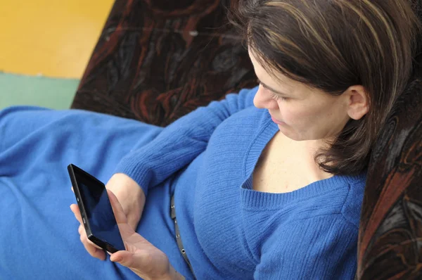 Femme assise sur le coach avec smartphone — Photo