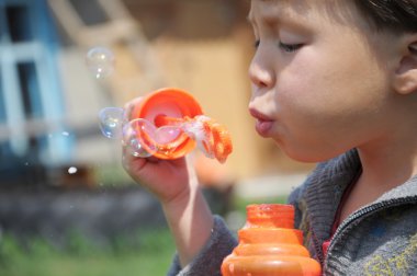Child making the soap bubbles clipart