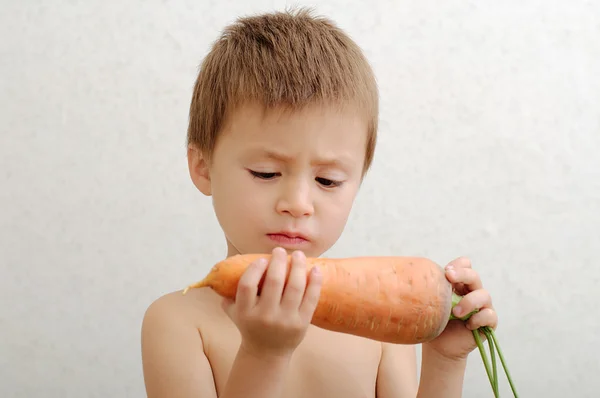 Boy looking at carrot. too tough. — Stock Photo, Image