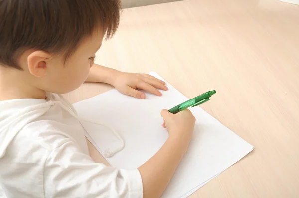 Jongen op wit papier schrijft — Stockfoto