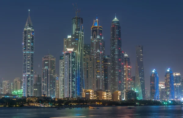 迪拜在蓝色小时，闪闪发光的灯和高的摩天大楼在傍晚清澄蓝的天空. — 图库照片