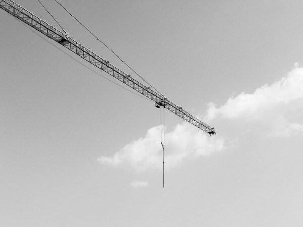 Building crane in a construction site over blue sky in black and white