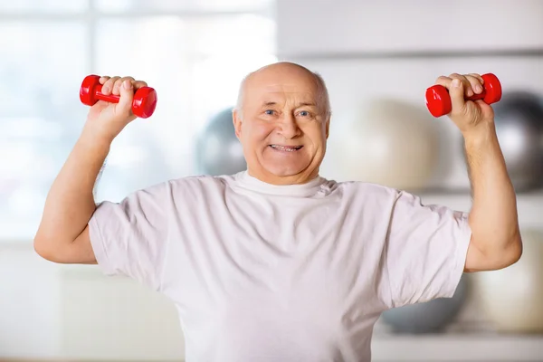 Hombre mayor sosteniendo pesas —  Fotos de Stock