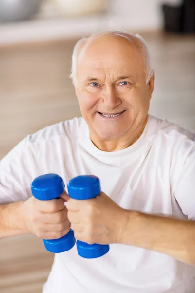 Hombre mayor sosteniendo pesas en el gimnasio —  Fotos de Stock