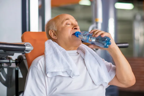 Приятный пожилой человек питьевая вода в тренажерном зале — стоковое фото
