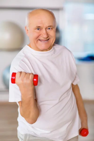 Positive senior man practicing with weights